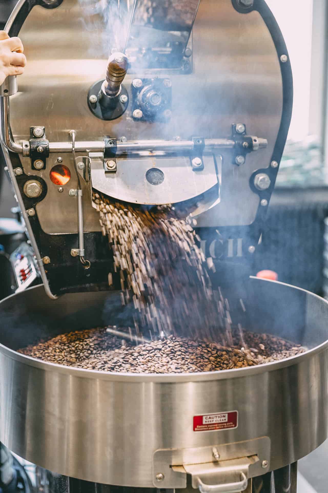 Kaffeebohnen fallen bei der Röstung aus der Röstmaschine in einen Auffangbehälter