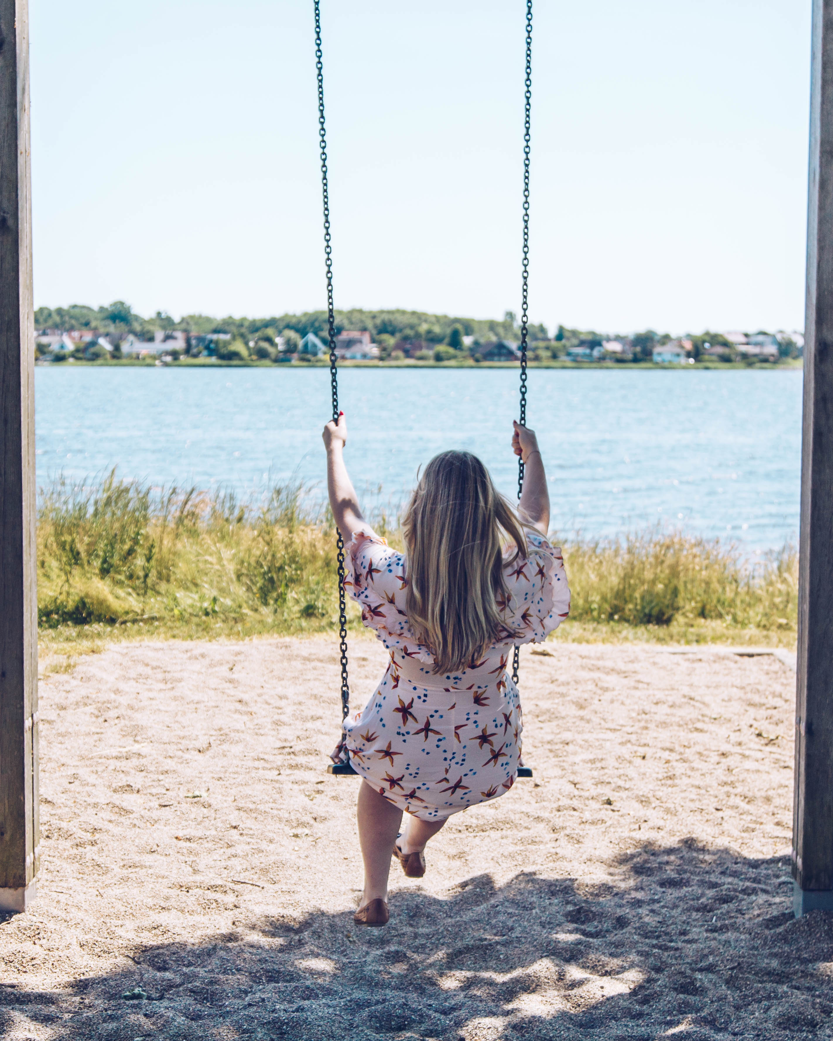 Finja sitzt auf einer Schaukel vor der Schlei