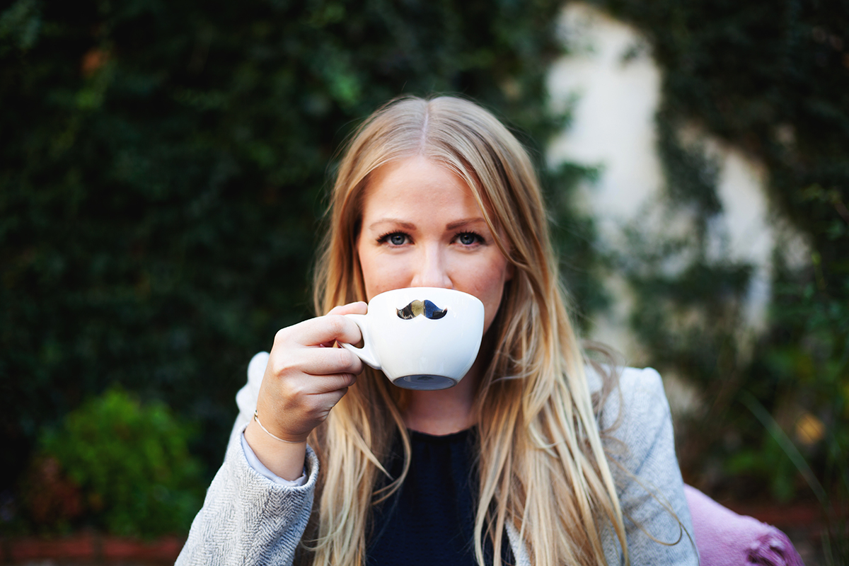 Finja sitzt draußen und trinkt aus einer Tasse