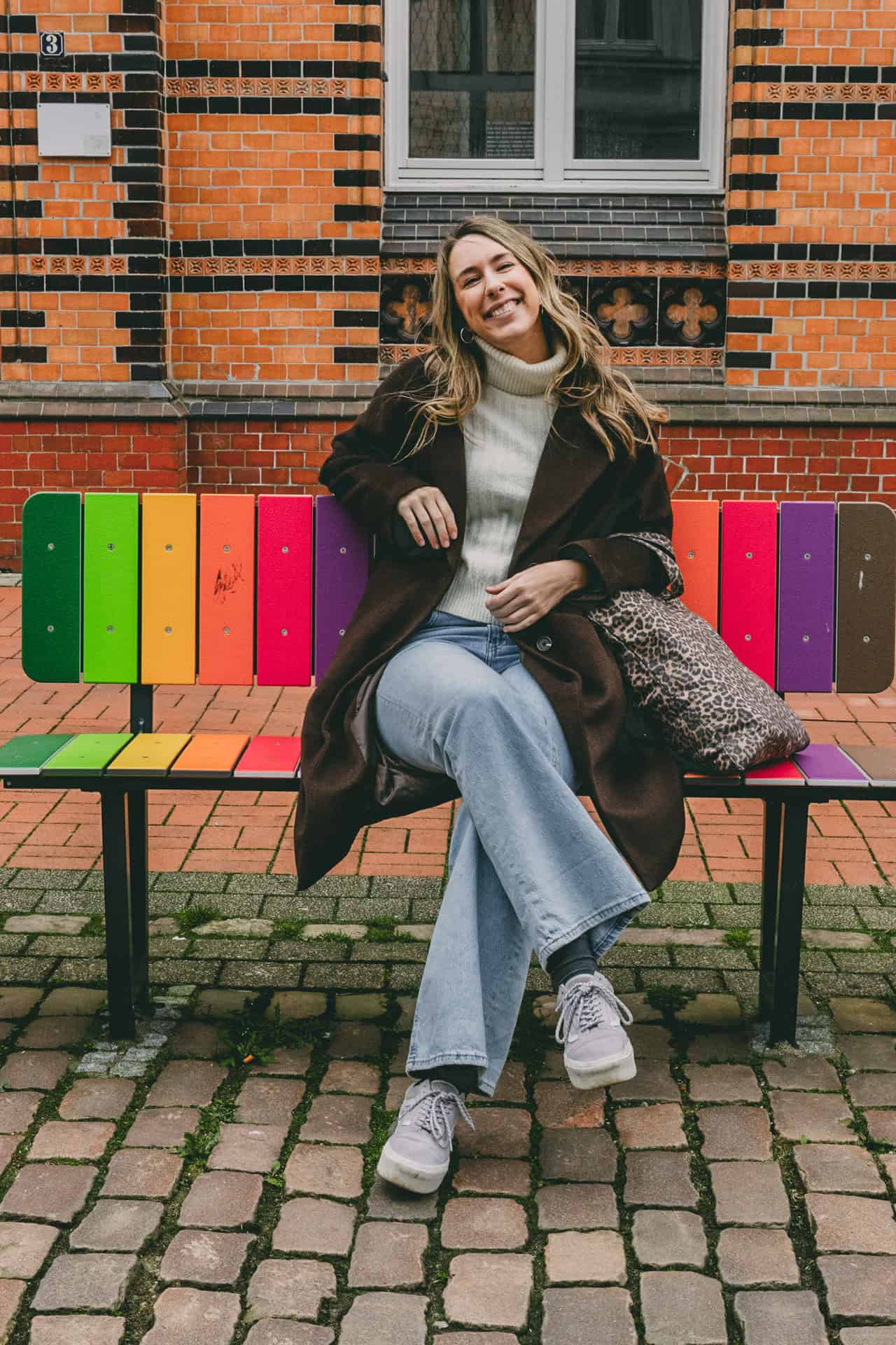 Finja T. auf einer regenbogenfarbenen Parkbank in der Rendsburger Innenstadt