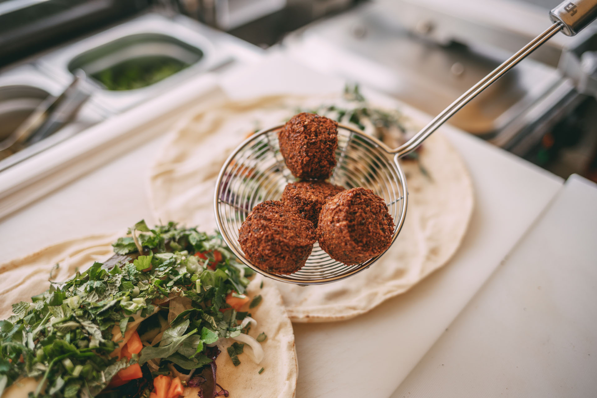 Eine Kelle mit frittierten Falafelbällchen