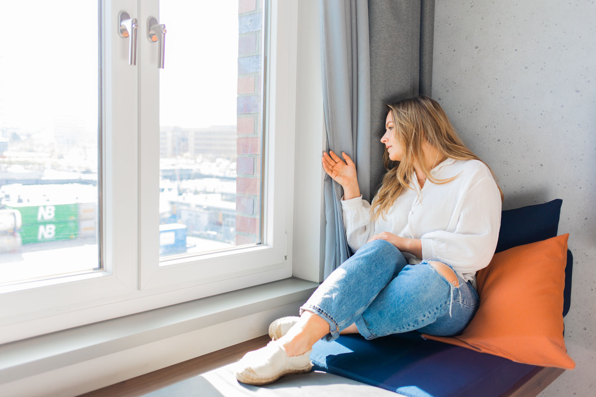 Sina liegt auf der gepolsterten Fensterbank in einem der Hotelzimmer und schaut aus dem Fenster