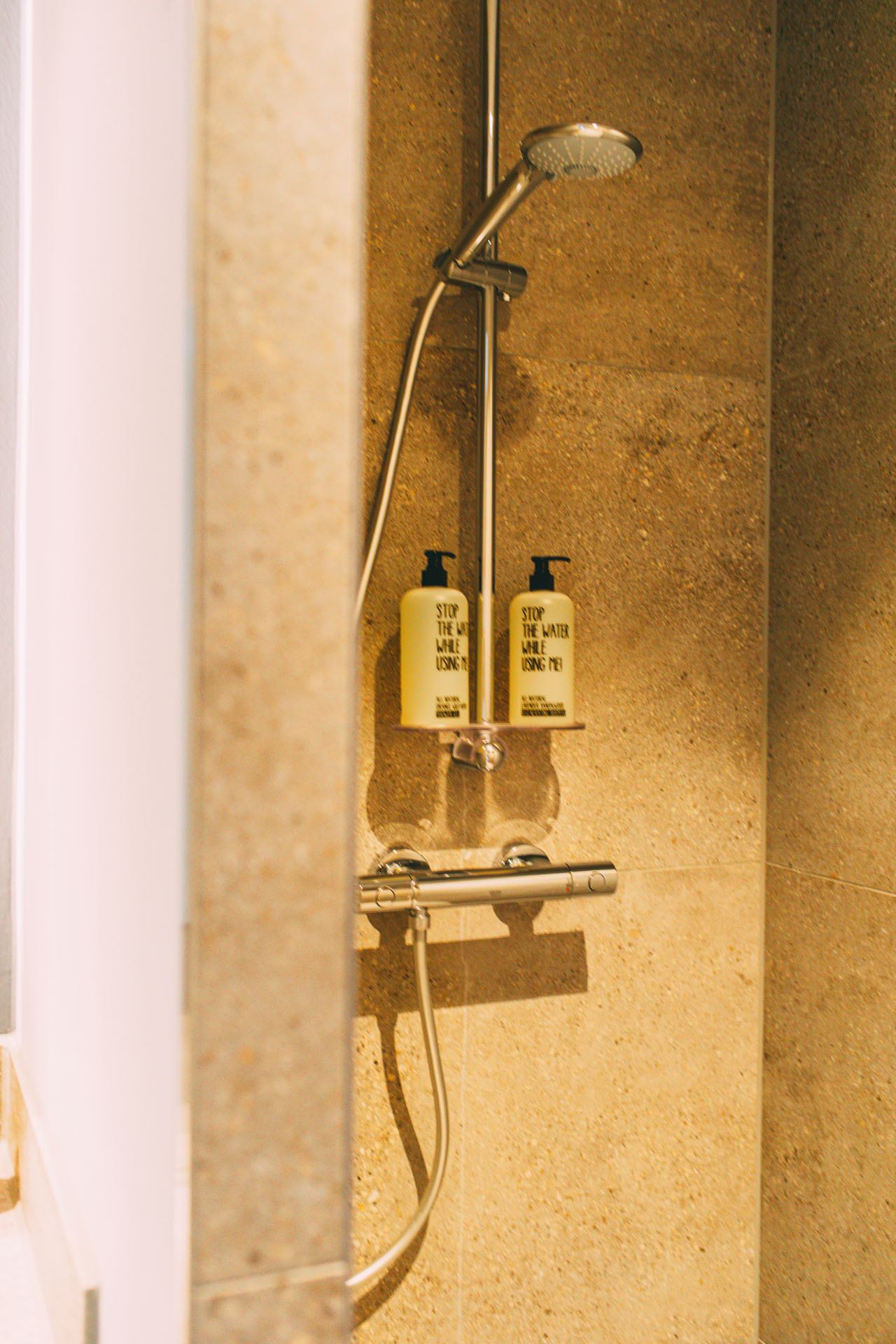 Die Dusche in einem der Hotelzimmer mit Duschgel und Shampoo der Marke Stop the water while using me
