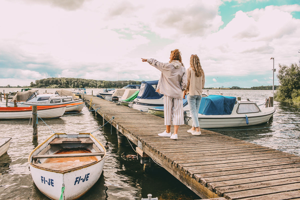 Mona und Finja laufen auf einem Steg. Links und rechts sind Boote im Wasser