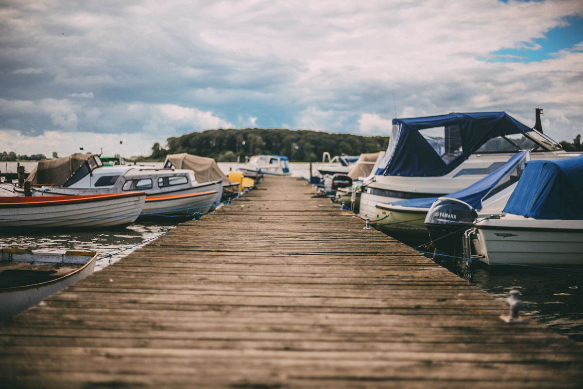 Ein Steg, links und rechts sind Boote im Wasser