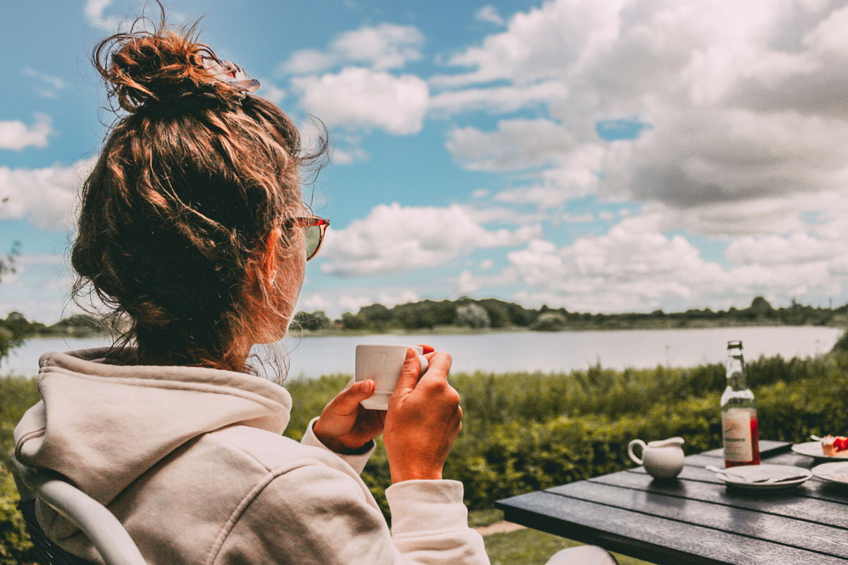 Mona trinkt einen Kaffee und blickt auf den See