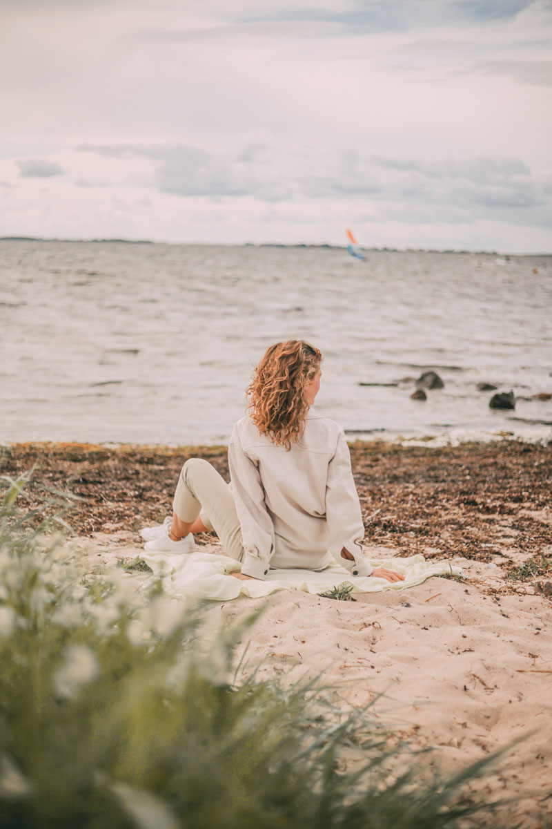 Mona sitzt am Strand und blickt auf das Meer