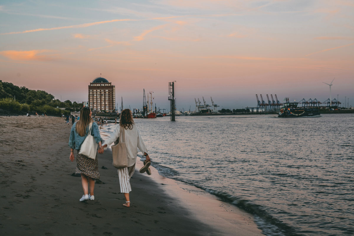 Mona und Finja gehen am Elbstrand entlang in der Abenddämmerung