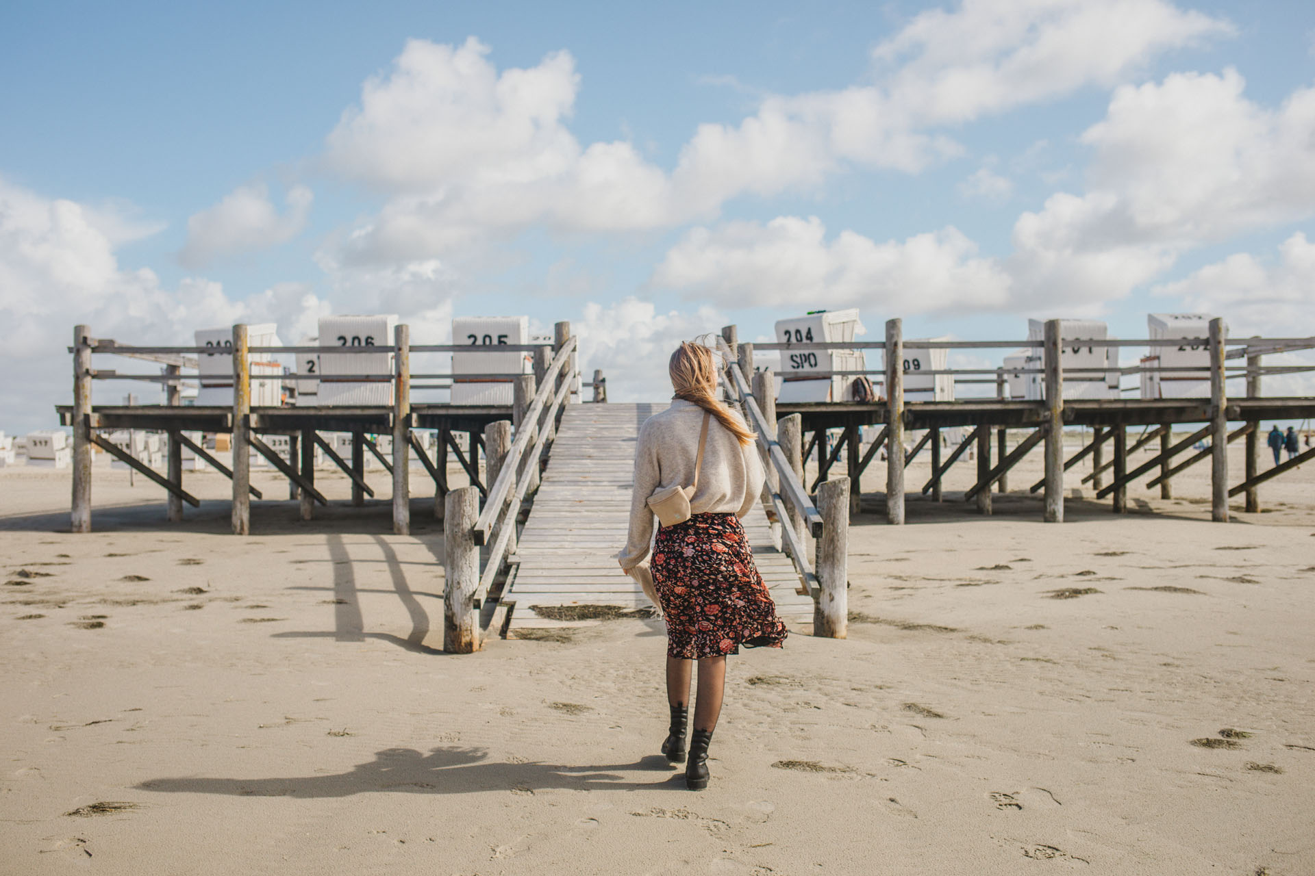 Finja läuft am Strand von St. Peter-Ording auf eine Pfahlbaute zu