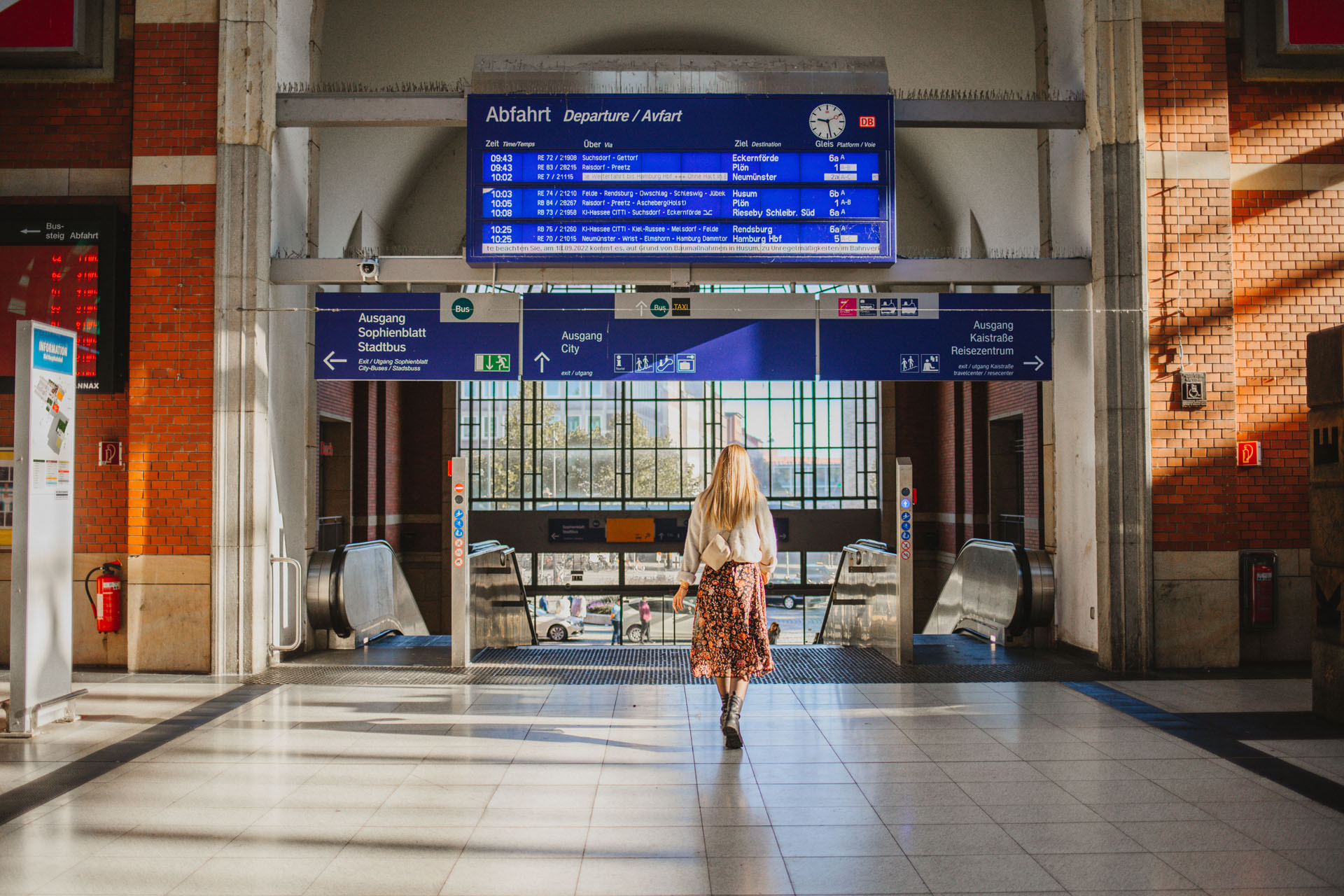 Finja steht in der Bahnhofshalle am Kieler Hauptbahnhof unter der Gleisanzeige