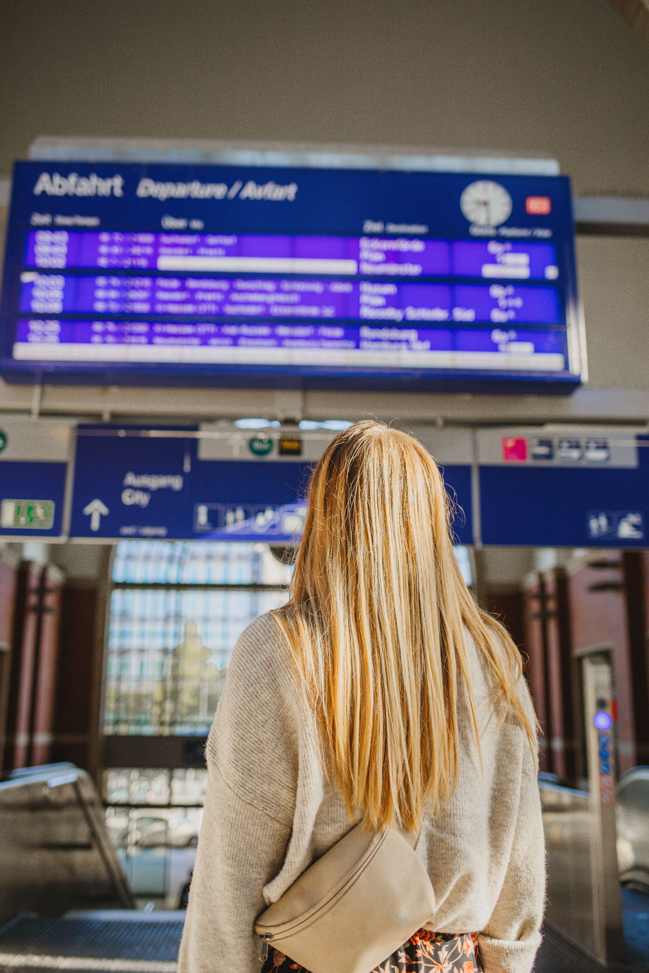 Finja steht in der Bahnhofshalle am Kieler Hauptbahnhof unter der Gleisanzeige