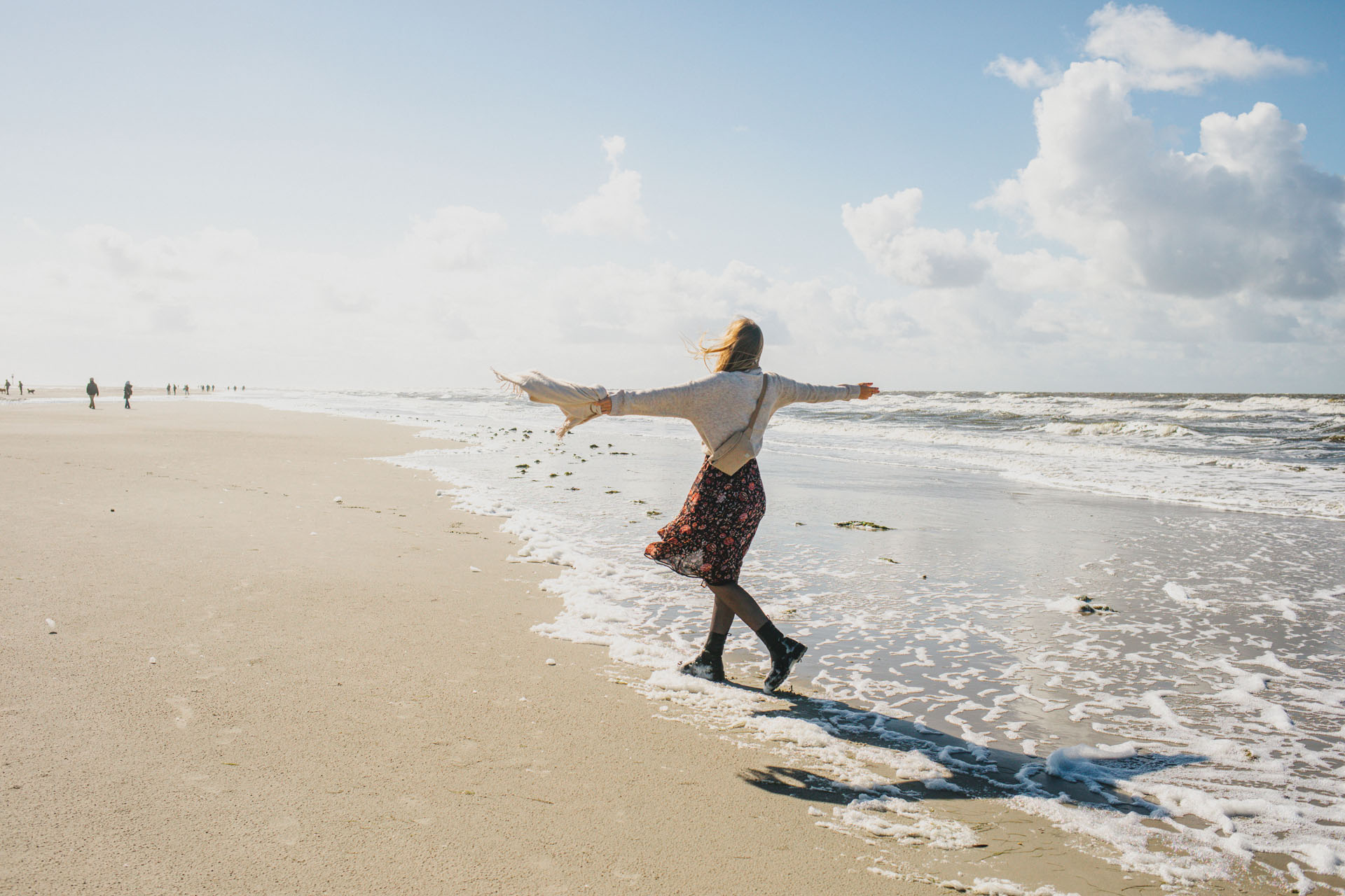 Finja mit ausgebreiteten Armen am Strand von St. Peter-Ording