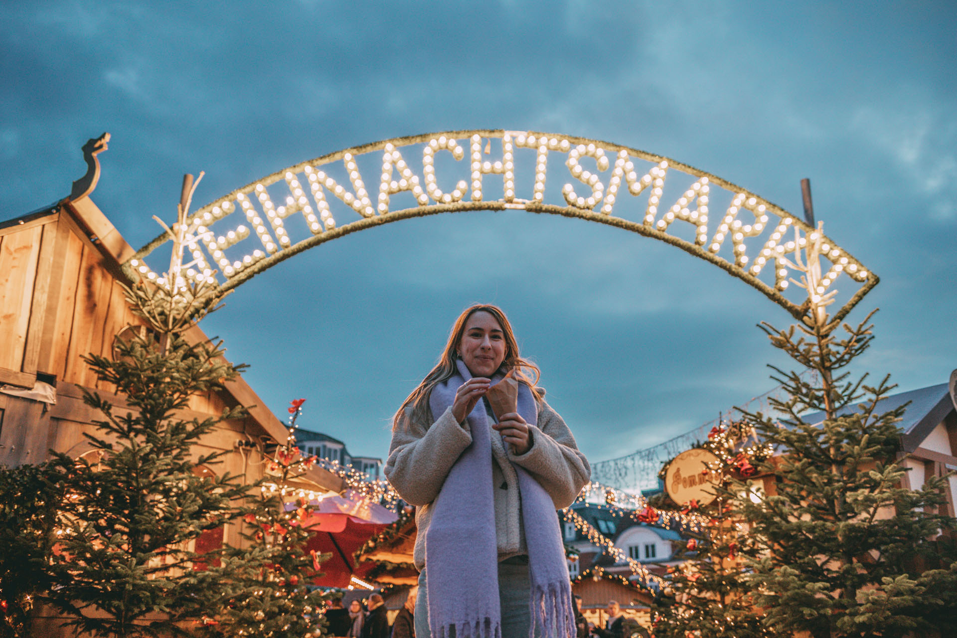 Finja steht vor dem Husumer Weihnachtsmarkt und isst gebrannte Mandeln