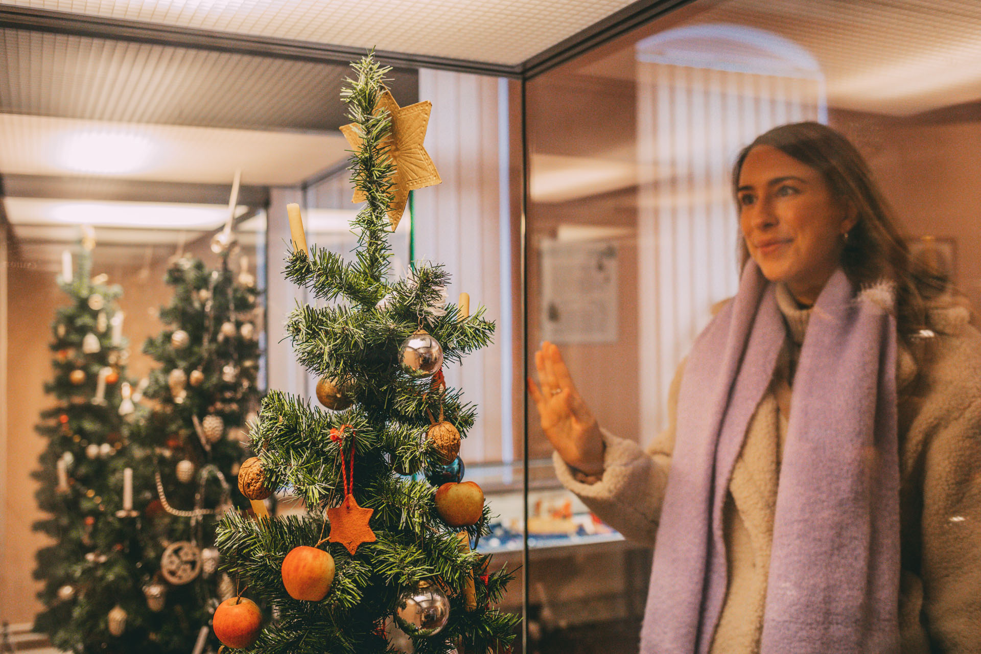 Finja schaut durch eine Vitrine auf einen geschmückten Weihnachtsbaum