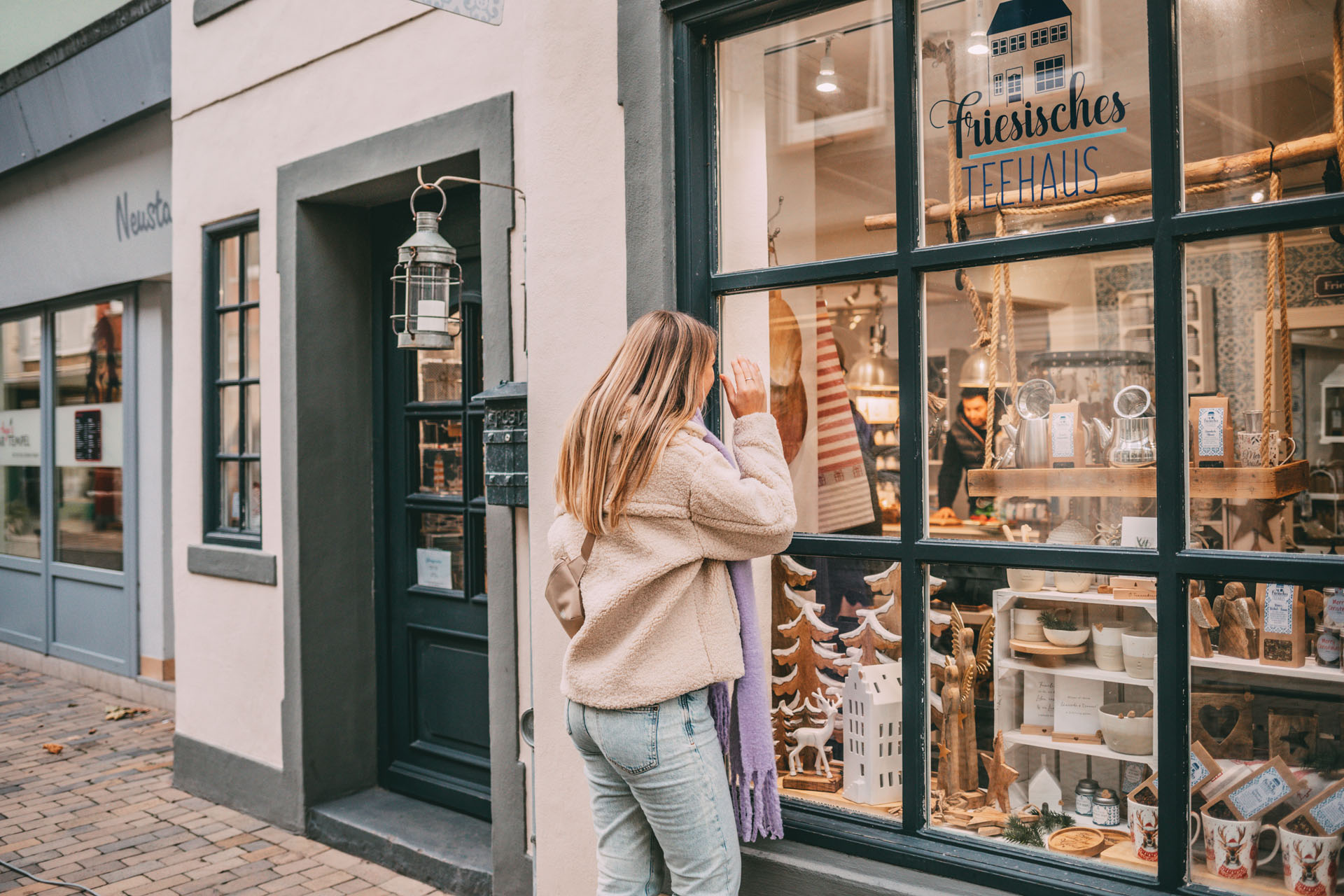 Finja schaut durch das Schaufenster in einen Teeladen.