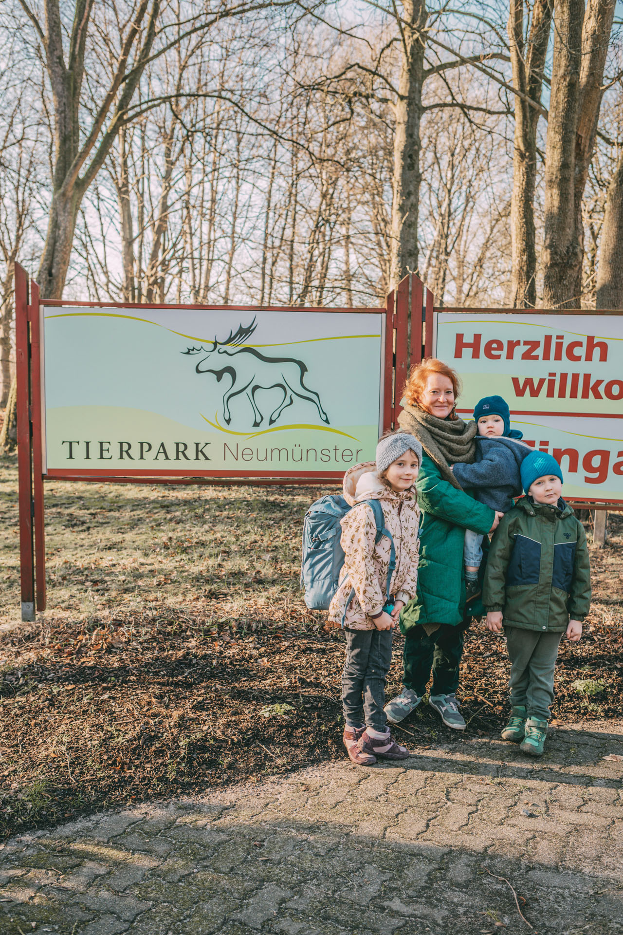 Eine Familie steht vor dem Willkommensschild vom Tierpark Neumünster