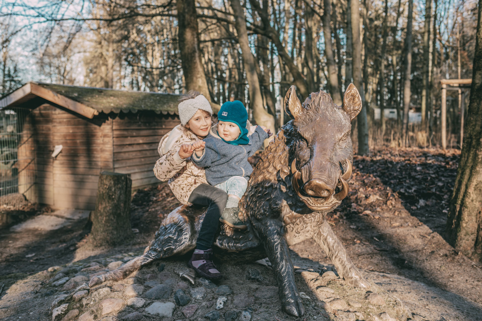 Zwei Kinder sitzen auf einer Wildschwein-Statue
