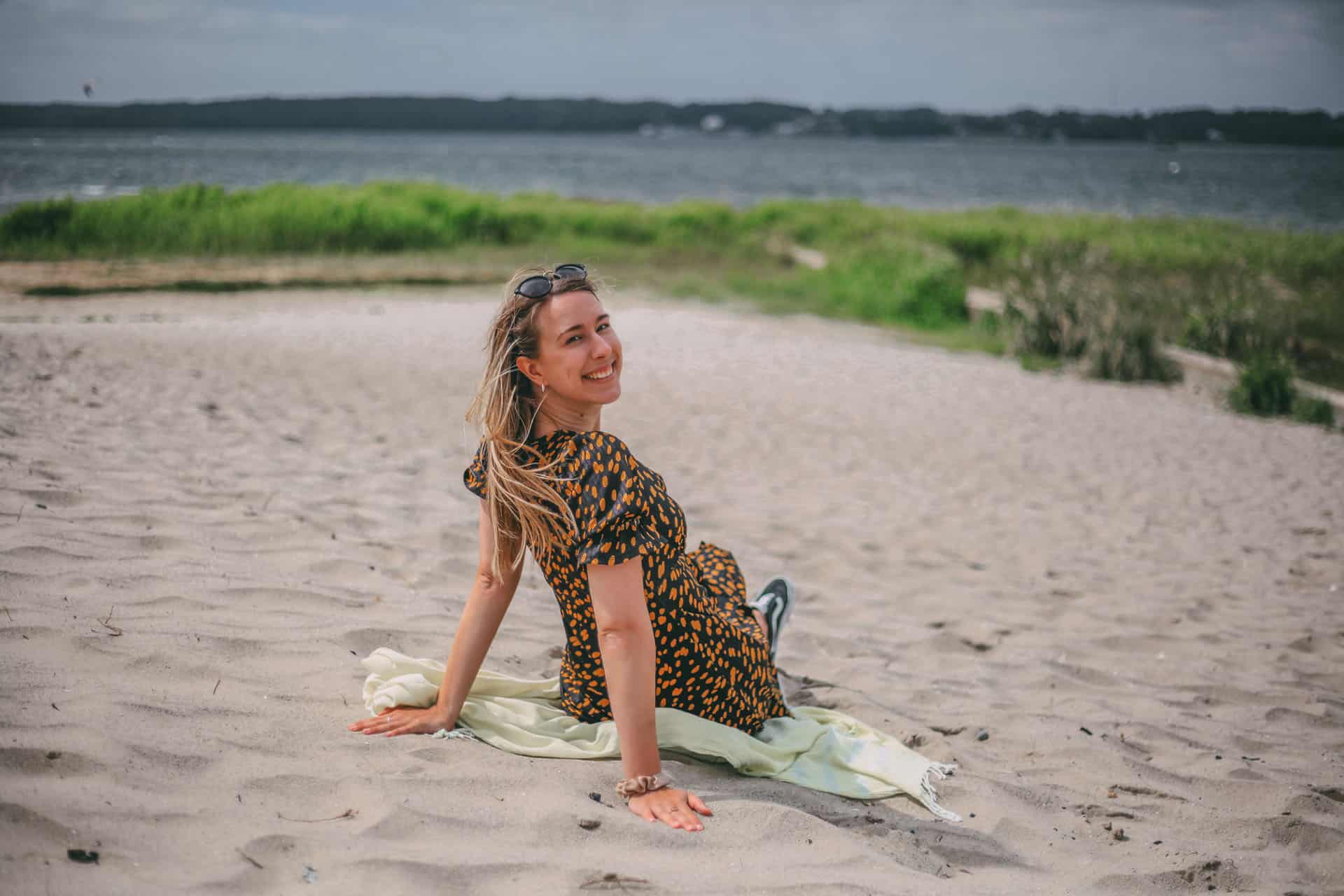 Finja sitzt am Strand Solitüde in Flensburg mit der Ostsee im Hintergrund