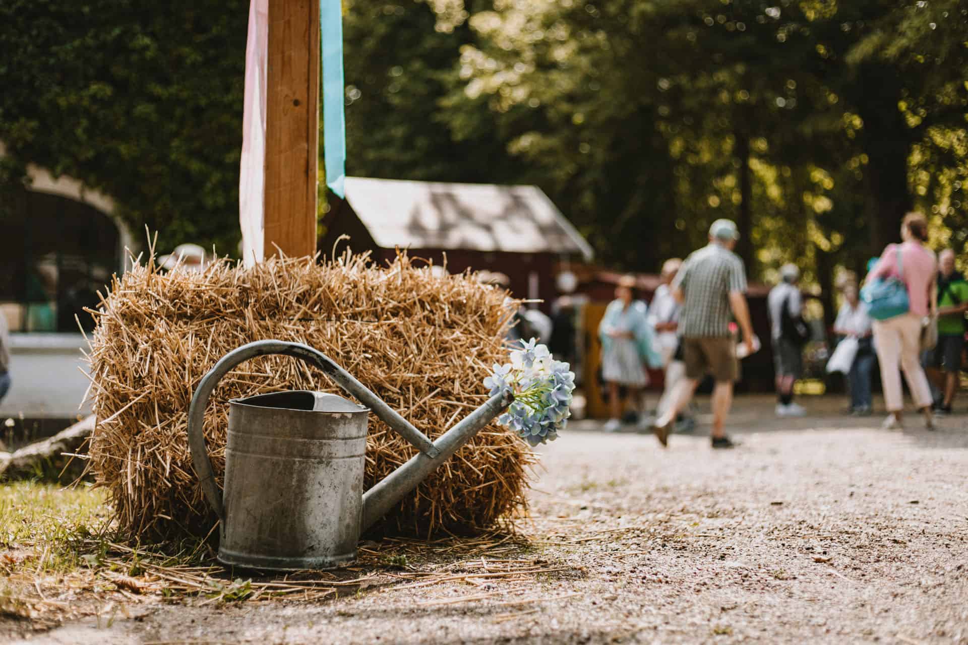 Eine Gießkanne steht vor einem Heuballen auf dem Boden