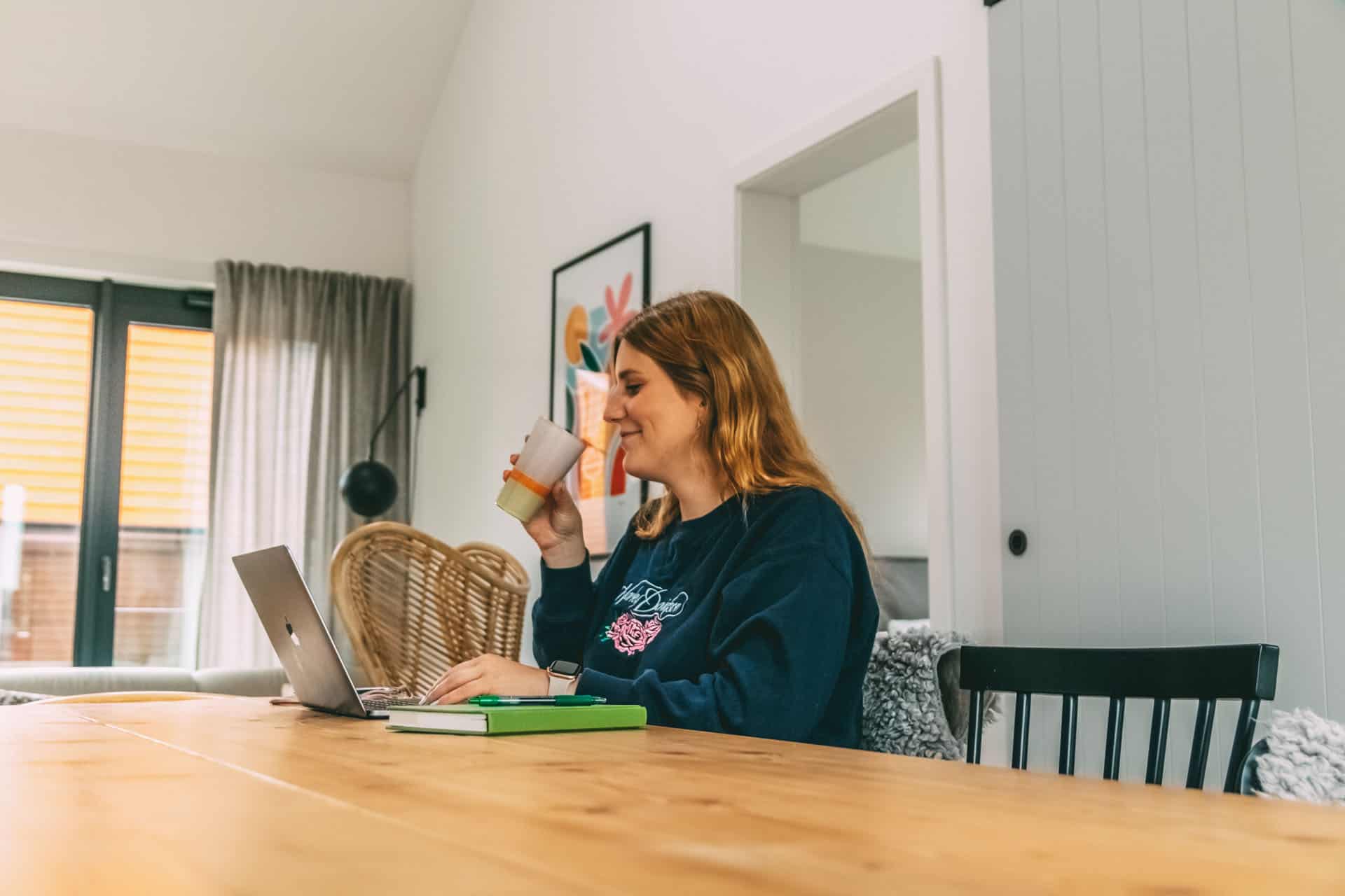 Maya sitzt am Tisch vorm Laptop und arbeitet