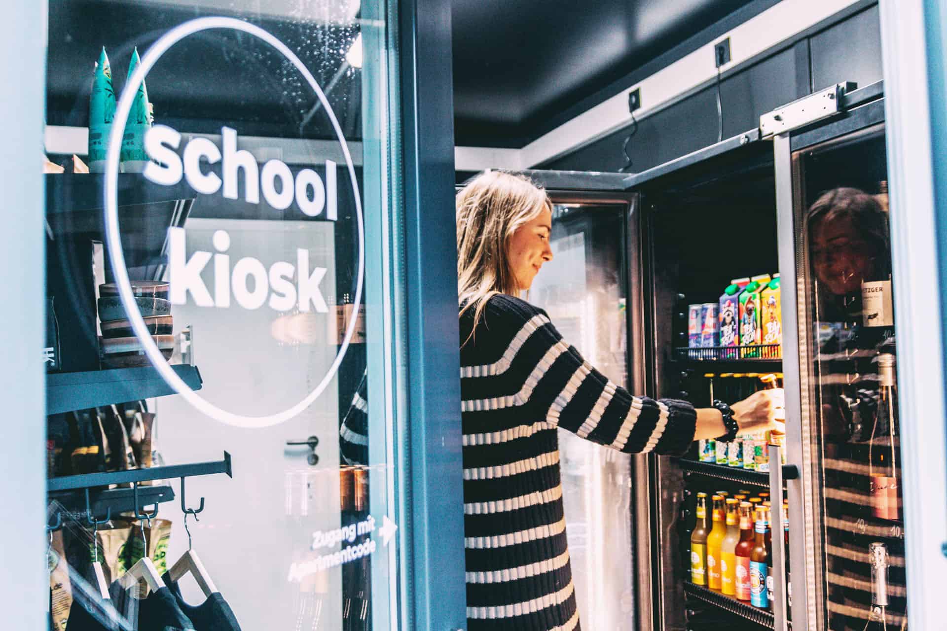 Finja nimmt sich im Schoolkiosk ein Getränk aus dem Kühlschrank