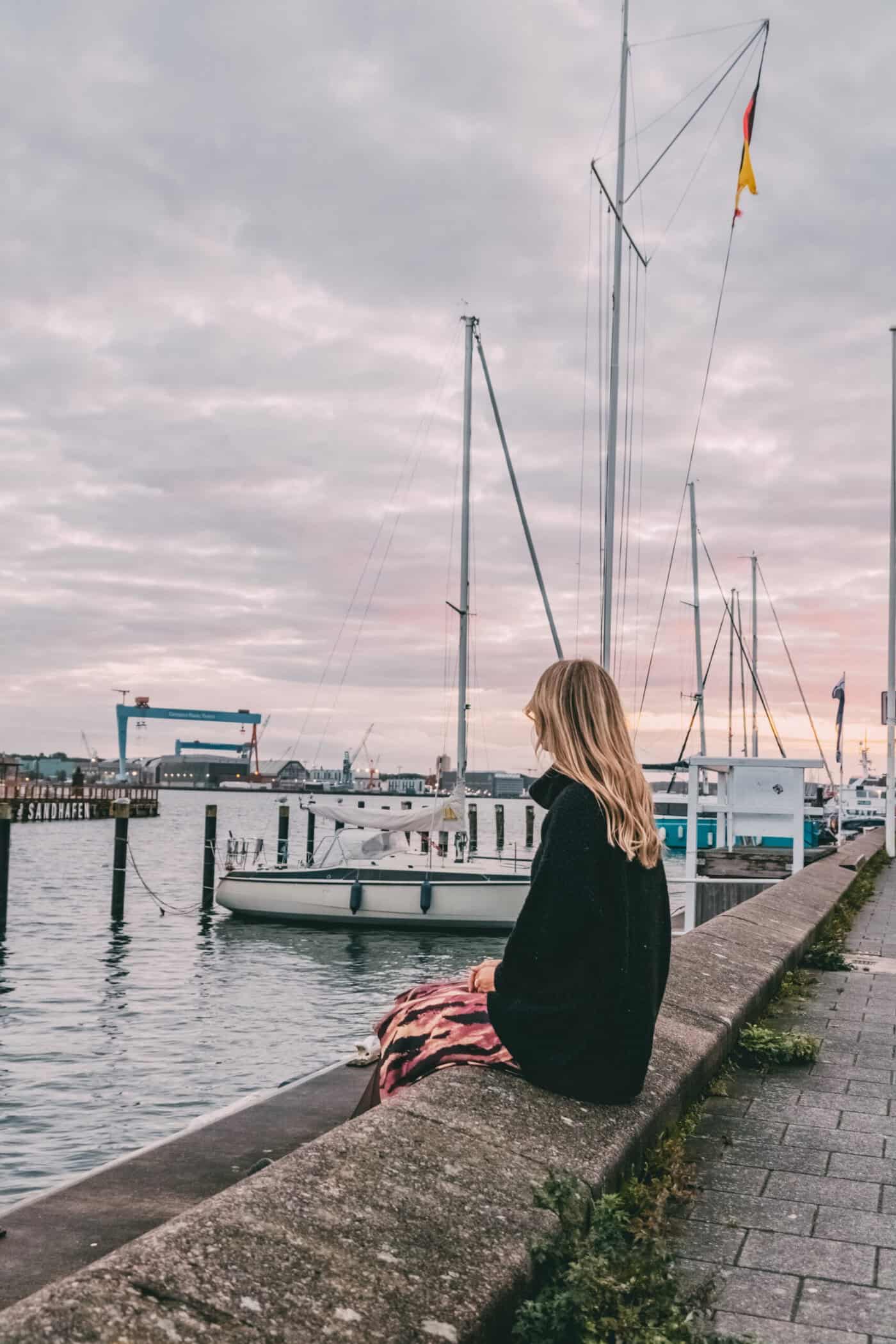 Finja sitzt an der Kiellinie mit Blick auf die Kieler Förde