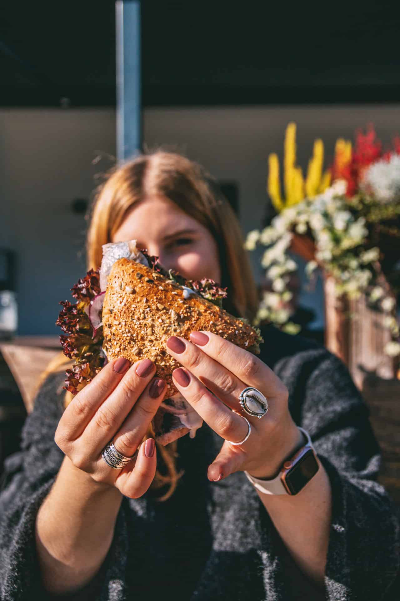 Maya hält ein Fischbrötchen in die Luft