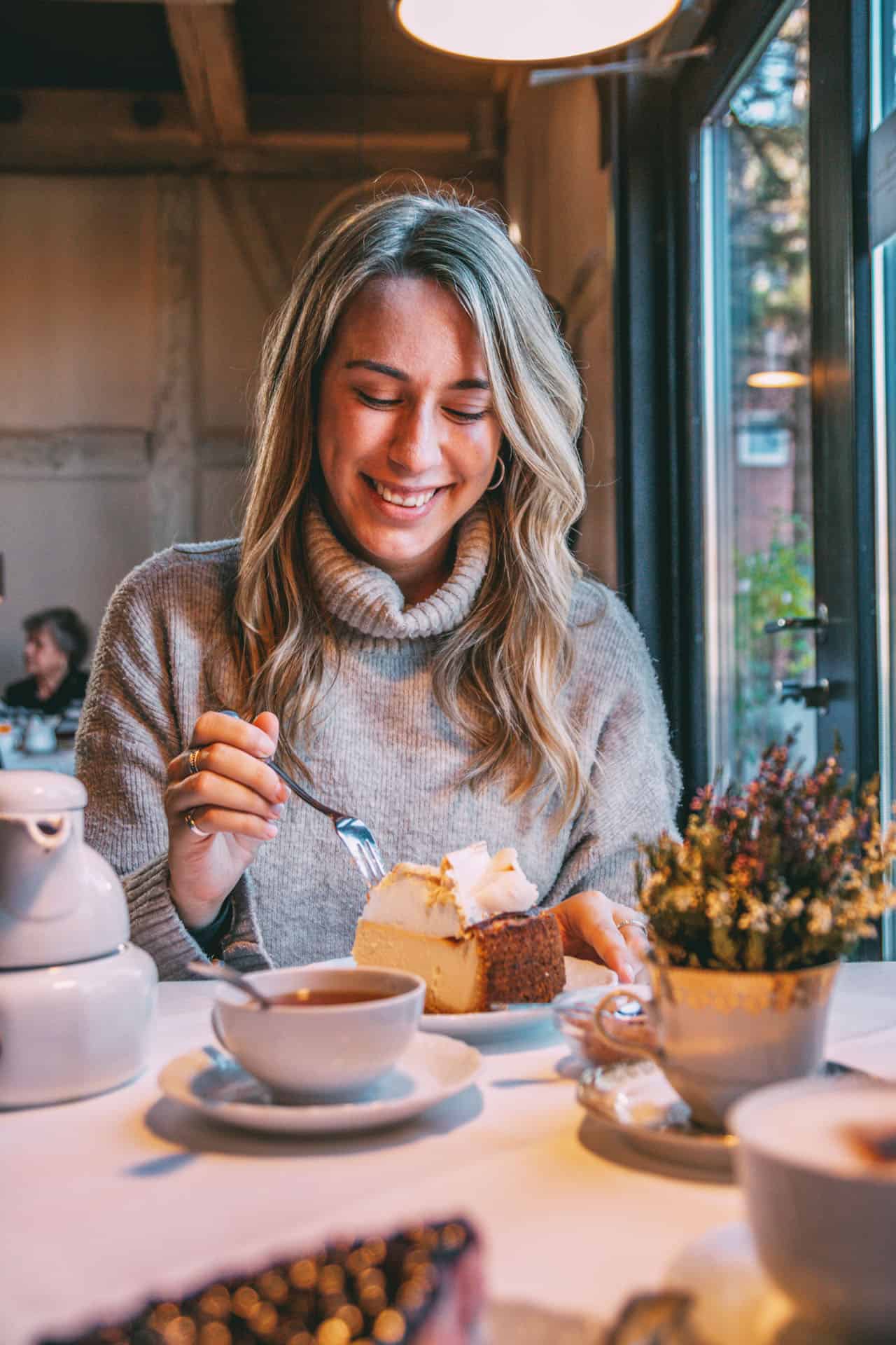 Finja sitzt im Café und sticht mit der Gabel in ein Stück Torte