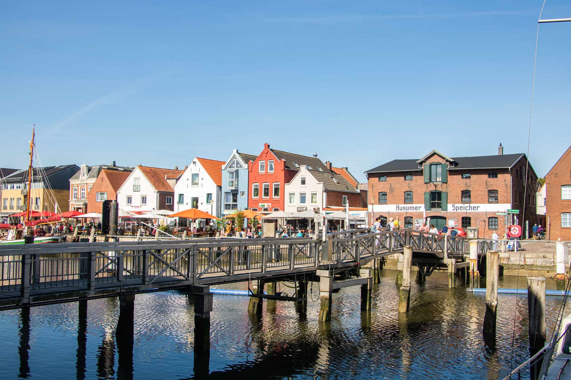 Mit dem Zug nach Husum: Foto des Hafenpanoramas. Bunte Fassaden und der Husumer Speicher. 