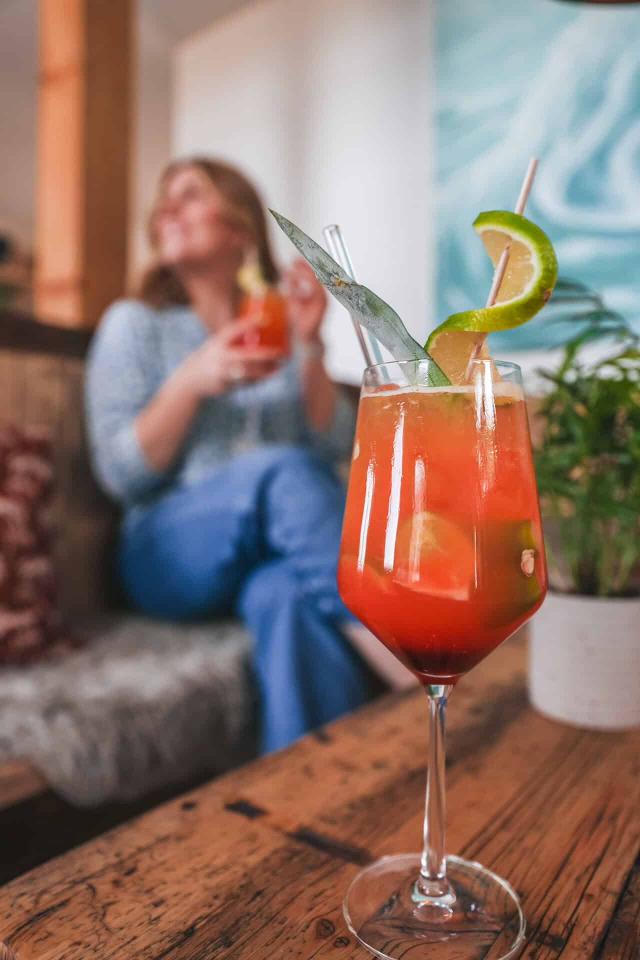 Ein Cocktail steht auf dem Tisch, Maya im Hintergrund