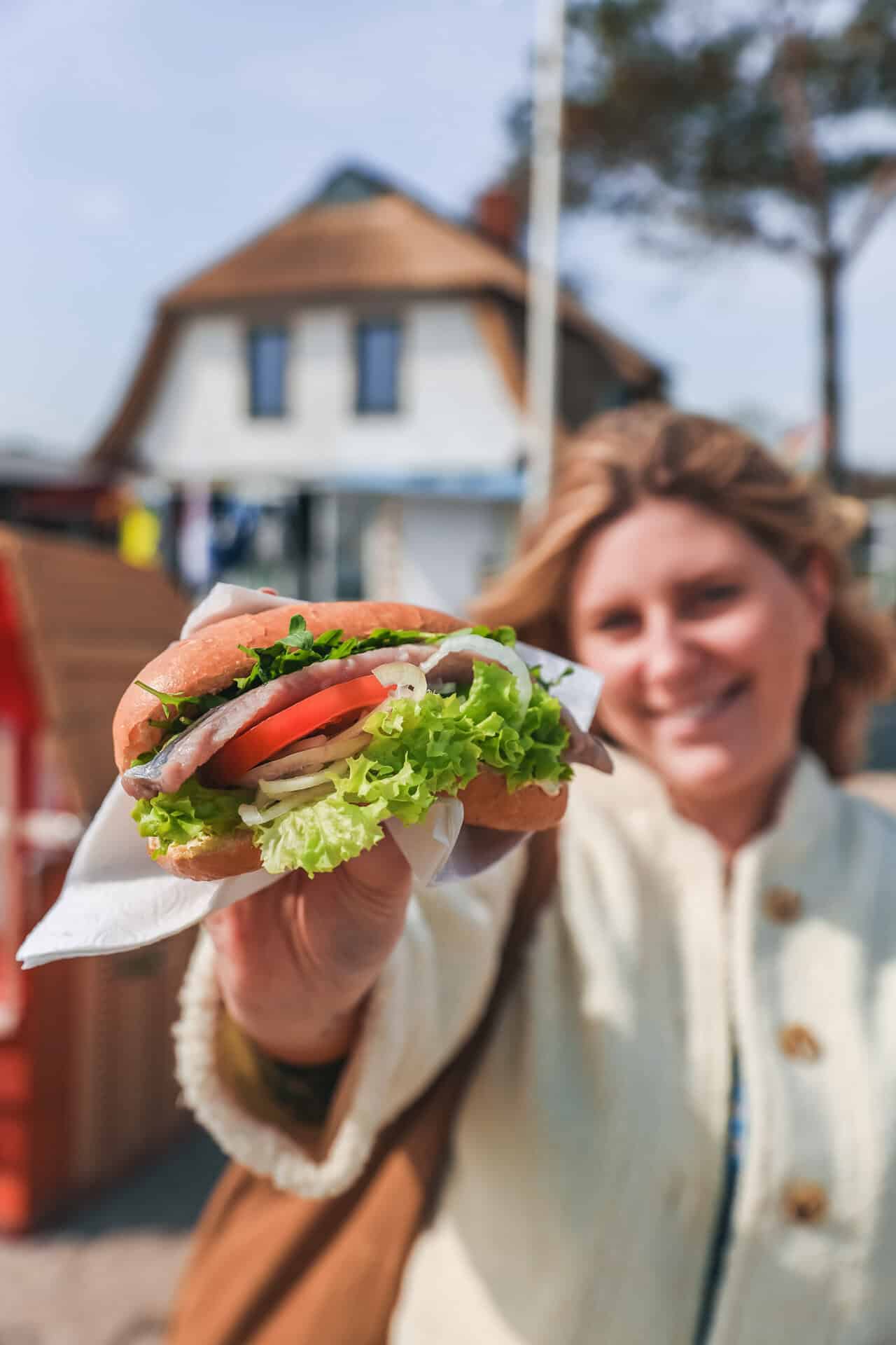 Maya hält ein Fischbrötchen in die Kamera