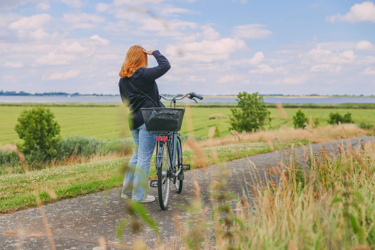 Maya steht mit ihrem Fahrrad auf dem Deich mit Blick Richtung Elbe