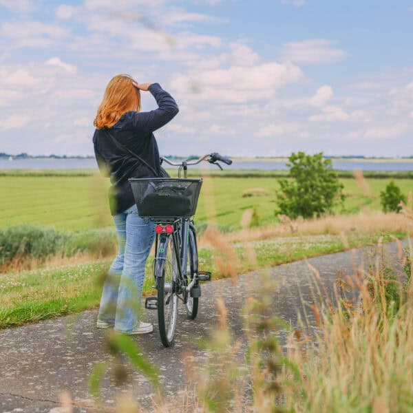 Maya steht mit ihrem Fahrrad auf dem Deich mit Blick Richtung Elbe